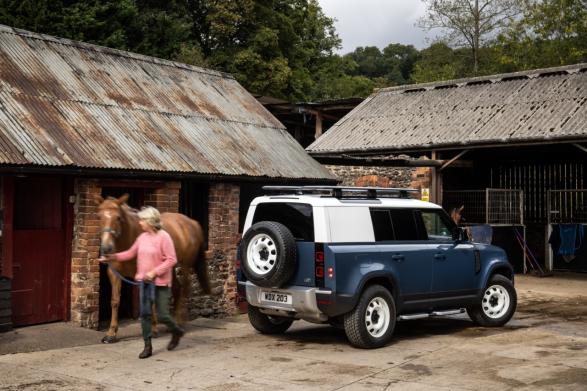 Frau führt Pferd neben Land Rover
